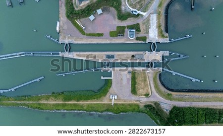 Top down drone view of the Lorentzsluizen on the Afsluitdijk in the Netherlands, showing the lock complex, waterway infrastructure and surrounding landscape from above.