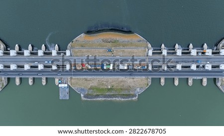 Top down drone view of the Lorentzsluizen on the Afsluitdijk in the Netherlands. Infrastructure image showing sluice gates, road traffic, water barriers, lock structures and Dutch water management from above.