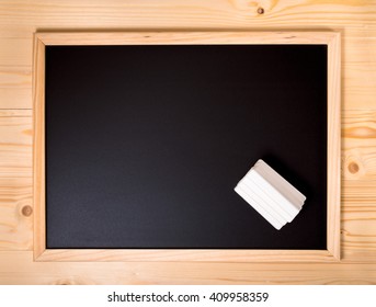 top down empty blank school black board with white chalks on wooden background, close up