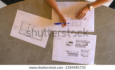 TOP DOWN: Female feng shui expert drawing energy lines on house building plan. Young woman analysing energy flow distribution and making feng shui plan for home residence and balanced interior design.