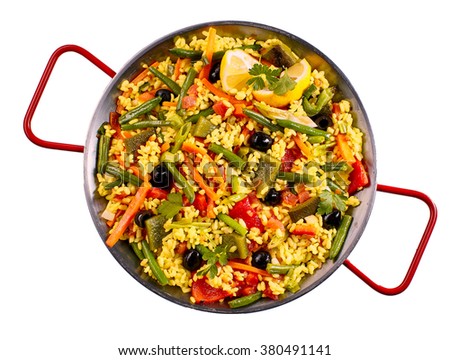 Top down first person perspective view of savory paella verdudas with yellow rice, beans, olives and other vegetables prepared in metal pan over white background