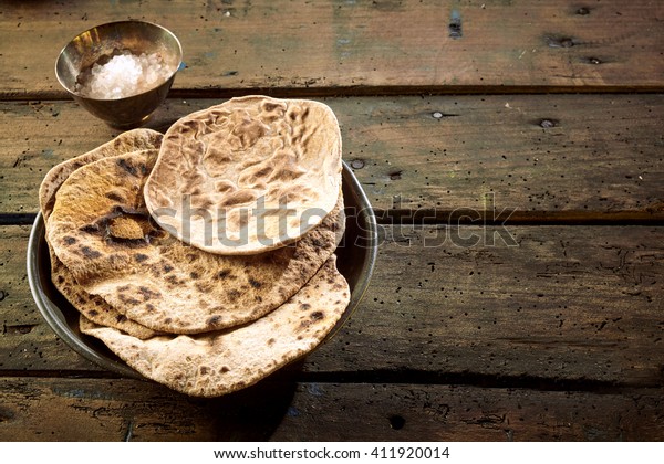 Top down first person\
perspective view on chapati bread beside cup and copy space on\
wooden table
