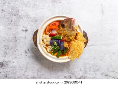 Top Down Flat Lay Asian Cooked Chinese Asia Food On Table, Single Dish. Curry Red Snapper Fish Head With Vegetables In A Claypot. Famous Singapore Malaysia Nonya Peranakan Dish.