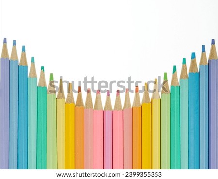 Top down or flat lay of a boarder of colorful pastel colored pencils isolated on a white background with cop space