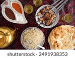 Top down flat lay of traditional Afghan food - skewers of chicken kebab with green tea and freshly baked naan bread. Bamiyan, Afghanistan.