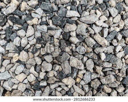 Top down fullframe view of natural grey gravel stones texture. Abstract overhead background of crushed granite rock pieces and pebbles, perfect for graphic design patterns, building materials concepts, and industrial backdrops.