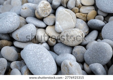 Top down ground capture displaying a chaotic but beautiful arrangement of entirely smooth rounded grey and white stones.