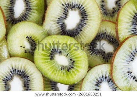 A top down macro view of a background of many fresh kiwi slices.