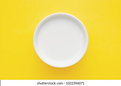 Top Down Minimalist View Of A Milk In A White Bowl On Yellow Background