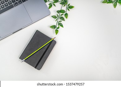 Top Down Notebook On A White Desk With Leaves And Laptop