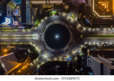 Top Down Overhead Aerial View Of Moving Car Traffic At Roundabout Vehicle Road Traffic Around Selamat Datang Monument In Jakarta, Indonesia At Night In 2021