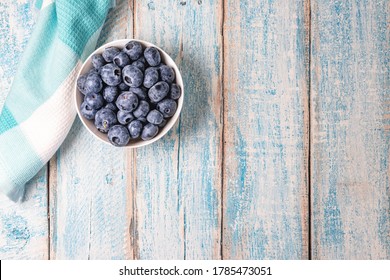 Top Down Overhead Shot Of A White Bowl Filled With Fresh Juicy Blueberries On A Rustic Weathered Worn Light Blue Wood Table Surface