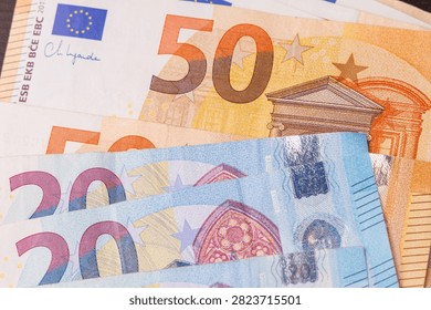 Top down overhead view of twenty and fifty euro banknotes scattered across the table surface, full frame background representing cash and investment