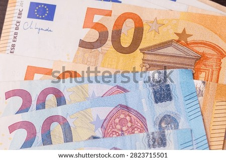 Top down overhead view of twenty and fifty euro banknotes scattered across the table surface, full frame background representing cash and investment