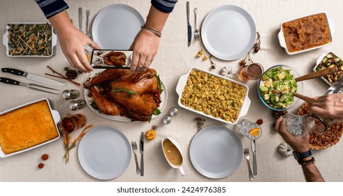 Top down photo of a thanksgiving holiday table spread. Persons arms taking phone picture of turkey.