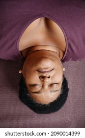 Top Down Portrait Of Black Senior Woman Lying On Floor With Eyes Closed While Enjoying Relaxation Exercise