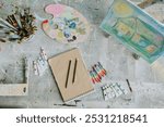 Top down shot of old dirty table with empty sketchbook and drawing equipment