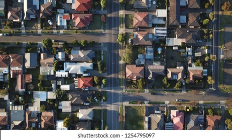 Top Down Street View Aerial Shot With Drone, Long Shadows Afternoon Sun, Rooftops And Symmetrical Roads