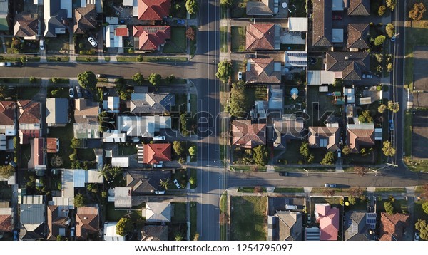 Top down street view\
aerial shot with drone, long shadows afternoon sun, rooftops and\
symmetrical roads