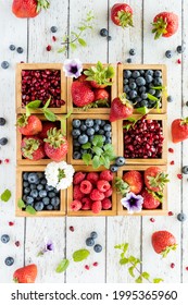 Top down vertical view of a compartment box filled with different types of berries and berries scattered all around.