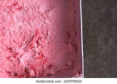 Top Down View Above Sweet Strawberry Pink Ice Cream Made From Real Fruit In White Paper Square Box Container With Dark Grey Or Black Stone Concrete Texture Background