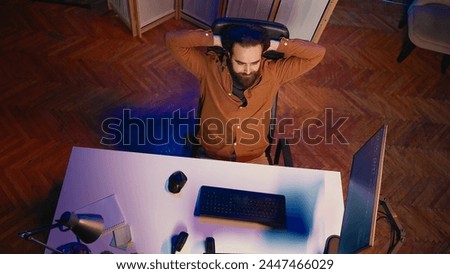 Top down view of IT admin in home office stretching after sitting on desk chair all day. Software engineer loosening up, relaxing after typing on computer for long period of time, aerial shot
