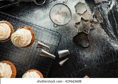 Top down view of artisan baker's table. Cookie cutters, cooling rack, cupcakes. Shallow depth of field, natural light and grain. - Powered by Shutterstock