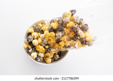 Top Down View Of A Bag Of Popcorn Poured Into A Bowl. Snack Is Isolated Against A White Background.