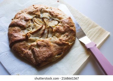 An Top Down View Of A Baked Apple Galette Next Of A Pink Spatula  