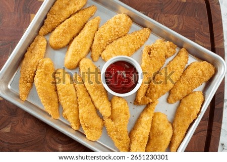 A top down view of a baking sheet of gluten-free chicken tenders.