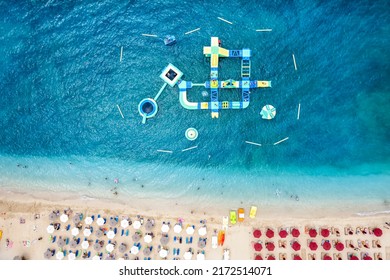 Top Down View To A Beautiful Beach With Fine Sand, Turquoise Sea And A Floating Water Play Park In The Sea