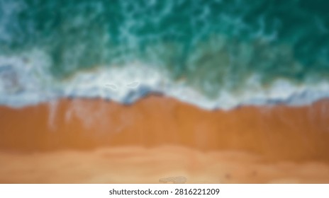Top down view of a beautiful sandy beach with clear turquoise water and white foamy waves gently rolling onto the shore.