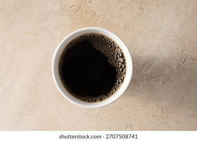 A top down view of a black coffee in a paper cup.