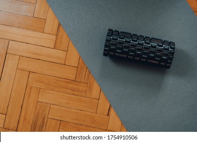 Top Down View Of A Black Foam Roller On A Fitness Mat Over Old Parquet Floor, Selective Focus. 