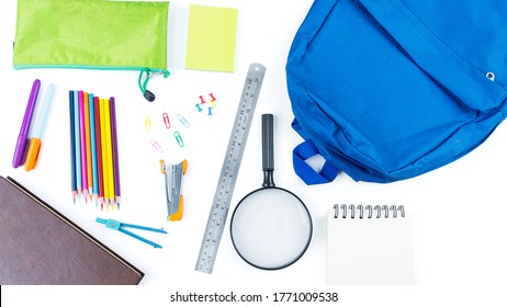 Top Down View Of Blue Backpack With Surrounded By School Supplies On The Table. Isolated On White Background