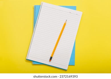 Top down view of blue notebook with yellow pencil on yellow background - Powered by Shutterstock