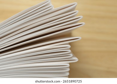 top down view of bookbinding signatures (unbound) standing up right on a defocused wooden surface