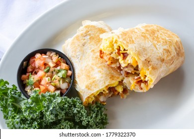 A top down view of a breakfast burrito, in a restaurant or kitchen setting.