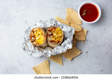 A top down view of a breakfast burrito in an unwrapped foil base.