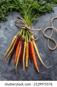 Top down view of a bunch of rainbow carrots bound together with rope.