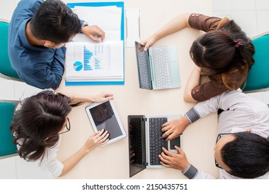 Top Down View Of Business People Discussing Together During A Business Meeting While Using Digital Device On The Table