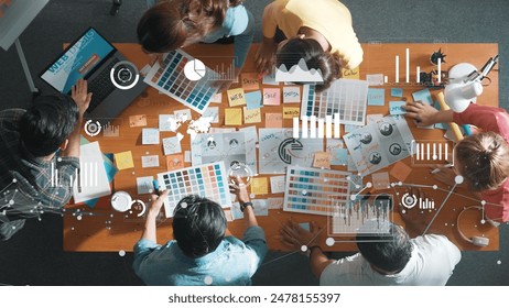 Top down view of business team with casual outfit looking laptop screen and sharing idea. Aerial view of manager works and checking color palette at table with statistic graph holographic. Symposium. - Powered by Shutterstock