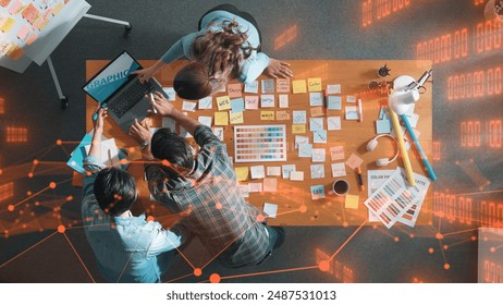 Top down view of business team with casual outfit looking laptop screen and sharing idea. Aerial view of manager works and checking color palette at table with statistic graph holographic. Symposium. - Powered by Shutterstock