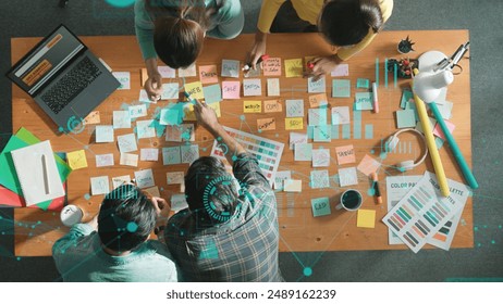 Top down view of business team with casual outfit looking laptop screen and sharing idea. Aerial view of manager works and checking color palette at table with statistic graph holographic. Symposium. - Powered by Shutterstock