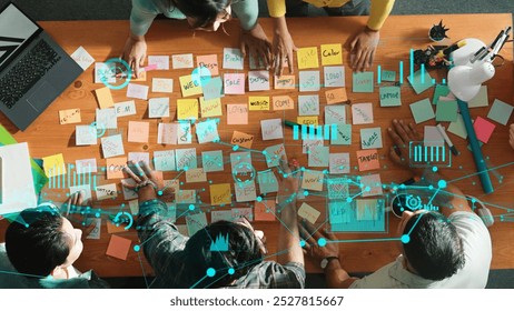 Top down view of business team with casual outfit looking laptop screen and sharing idea. Aerial view of manager works and checking color palette at table with statistic graph holographic. Symposium. - Powered by Shutterstock