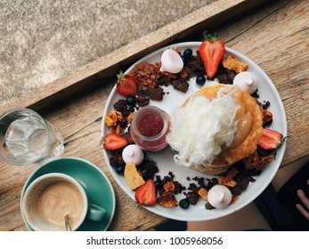 A Top Down View Of Cafe Food In Melbourne Australia - Pancake Stacks With Raspberry Sauce, Peanut Butter Decorated With Strawberries, Blueberries, Honeycomb, Candy Floss And Brownie Cookies.