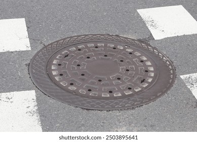 Top down view of a circle pattern metal manhole cover on floor
