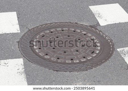 Top down view of a circle pattern metal manhole cover on floor