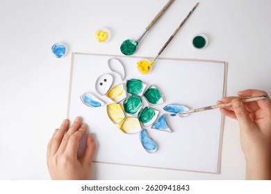 top down view of close up of hands painting activity, toilet paper roll rings turtle art idea, funny craft and DIY project for parents with children 