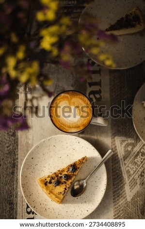Top Down View of Coffee Latte Art with Blueberry Tart Slice in Aesthetic Cafe Setting.